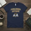 Navy blue t-shirt with "PUBLISHED AUTHOR" text in gold varsity letters above an open book graphic with a feather quill