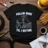 Lineman wearing protective gear pulling wire from a spool truck, with text "Pullin Wire Til I Retire" above and below