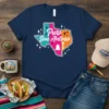 Navy blue t-shirt with "Puro San Antonio" text inside a colorful Texas outline, featuring a bell and tower graphic