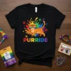Black t-shirt with "PURRIDE" text in rainbow colors and a cartoon cat wearing rainbow sunglasses, surrounded by colorful splashes and