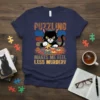Black cat assembling a puzzle on a navy t-shirt with the text "Puzzling Makes Me Feel Less Murdery"