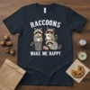 Raccoons Make Me Happy t-shirt design featuring three cartoon raccoons, one holding a donut, another wearing sunglasses, and the third