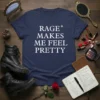 White text "RAGE* MAKES ME FEEL PRETTY" on a navy blue t-shirt, styled with boots and makeup