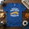 Text "RAISED ON CUBAN BREAD AND CROQUETAS" with cartoon loaf of Cuban bread and croquetas on a blue t-shirt
