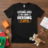 Raising Kids Is Like Herding Cats text design on a black t-shirt with playful typography and floral accents