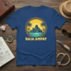 Raja Ampat t-shirt design featuring a circular graphic of a tropical island scene with mountains, palm trees, and ocean, with