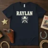 Navy t-shirt with "RAYLAN" in bold white letters above a western shield with crossed revolvers and cowboy hat