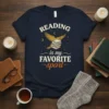 T-shirt with "Reading Is My Favorite Sport" text, featuring a bird flying over stacked books under a starry sky