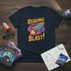 Reading Is A Blast slogan with a rocket ship graphic on a navy t-shirt, perfect for book lovers