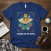 Reading on the moon t-shirt design featuring a cat wearing glasses reading a book on a large open book with
