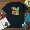 Ready to Crush TK text with a cartoon lion holding a pencil and books on a black t-shirt, designed for