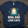 Real Dad Love Cats t-shirt featuring a cute cartoon cat wearing a crown sitting on a chair with a coffee