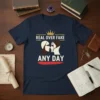 Real Over Fake Any Day quote with crown and profile graphics on a navy t-shirt