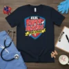 Navy blue t-shirt with "Real Super Heroes Wear Scrubs" text in a shield design, featuring a syringe graphic