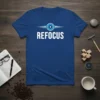 Blue t-shirt with the word REFOCUS in white, accompanied by a stylized camera lens graphic