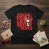 Black t-shirt with red groovy alphabet design spelling out ABCDE FGHIJK LMNOP QRSTUV WXYZ, featuring hearts and bunnies