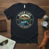 River Life Is The Good Life circular design with canoe, river, mountains, and campfire on a navy blue t-shirt