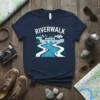 Riverwalk T-Shirt featuring a scenic cityscape with a bridge over a winding river and people walking, in white and blue