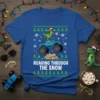 Roaring Through The Snow T-Shirt featuring a green dinosaur wearing a Santa hat and Christmas lights, riding a blue monster