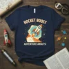 Navy blue t-shirt with "ROCKET BOOST ADVENTURE AWAITS!" text and a cartoon rocket launching through clouds and stars