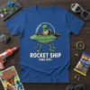Rocket Ship Take Off! text with an alien in a spaceship graphic on a blue t-shirt