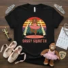 Sassy Squatch Ballet T-Shirt design featuring a Bigfoot ballerina in a pink tutu, mountains, and spotlights