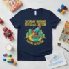 Saturday Morning Cereal And Cartoon Fueling Adventure t-shirt with rocket, cereal bowl, and city skyline graphic