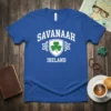 Savanaah Ireland T-Shirt with a white shield featuring a green shamrock and Celtic knot accents. Text reads "SAVANAAH" above and