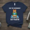 Navy blue t-shirt with "Save the Environment Eat Plastic" text and a cartoon cat holding plastic
