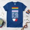 T-shirt with "Say Gay Say Trans Say Love Say Equality" text and rainbow and trans flags, featuring white and red