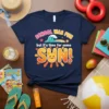 T-shirt with text "SCHOOL WAS FUN but it's time for some SUN!" featuring a cute smiling sun graphic and ocean
