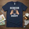 Navy blue t-shirt with white text "SCISCOR ME DADDY" and hands forming scissors graphic, funny fatherhood design