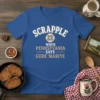 Blue t-shirt with white and gold text "SCRAPPLE WHEN PENNSYLVANIA SAYS GUDE MARIYE" and a decorative Pennsylvania Dutch folk art