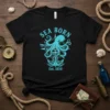 Black t-shirt with turquoise SEA BORN Est. 1850 design featuring an octopus, anchor, and compass
