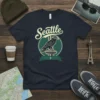 Seattle Eagle graphic t-shirt design featuring a retro-style eagle wearing sunglasses, perched atop the Space Needle, with "Seattle" text above