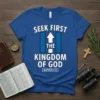 Christian t-shirt with white text "SEEK FIRST THE KINGDOM OF GOD MATTHEW 6:33" and a blue graphic with an upward