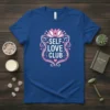 Self Love Club t-shirt with pink lotus and heart graphic, featuring white text on a blue shirt