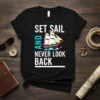 Set Sail And Never Look Back quote with a colorful sailing ship graphic on a black t-shirt