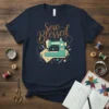 Sew Blessed t-shirt design with a teal sewing machine, spools of thread, needles, and scissors