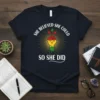 T-shirt with "She Believed She Could So She Did" text and a raised fist graphic with a growing plant and