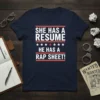 She Has A Resume He Has A Rap Sheet quote on a navy t-shirt, featuring bold white and red text