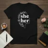 She her pronoun t-shirt with floral wreath around profile of a woman. White text and design on black shirt