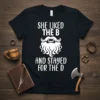 Black t-shirt with white text "SHE LIKED THE B AND STAYED FOR THE D" and a stylized beard and mustache