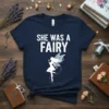 Navy blue t-shirt with white text "SHE WAS A FAIRY" and a white silhouette of a fairy with blue wings