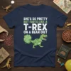 Funny t-shirt design: "SHE'S SO PRETTY BUT FARTS LIKE A T-REX ON A BEAN DIET" text with a cartoon T-Rex