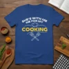 Blue t-shirt with white text "SHE'S WITH ME ME FOR MY" above a chef's hat and yellow text "COOKING" with