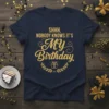 Navy t-shirt with golden text "SHHH, NOBODY KNOWS IT'S MY Birthday" in script font, surrounded by a laurel wreath with