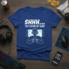 SHHH... I'M PLAYING MY GAME t-shirt with a gamer wearing headphones and holding a controller in front of a pixelated