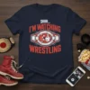 Navy blue t-shirt with bold red text "SHHH... I'M WATCHING WRESTLING" featuring a wrestling championship belt graphic