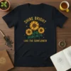 Shine Bright Like The Sunflower text with three yellow sunflowers and small stars graphic on a black t-shirt